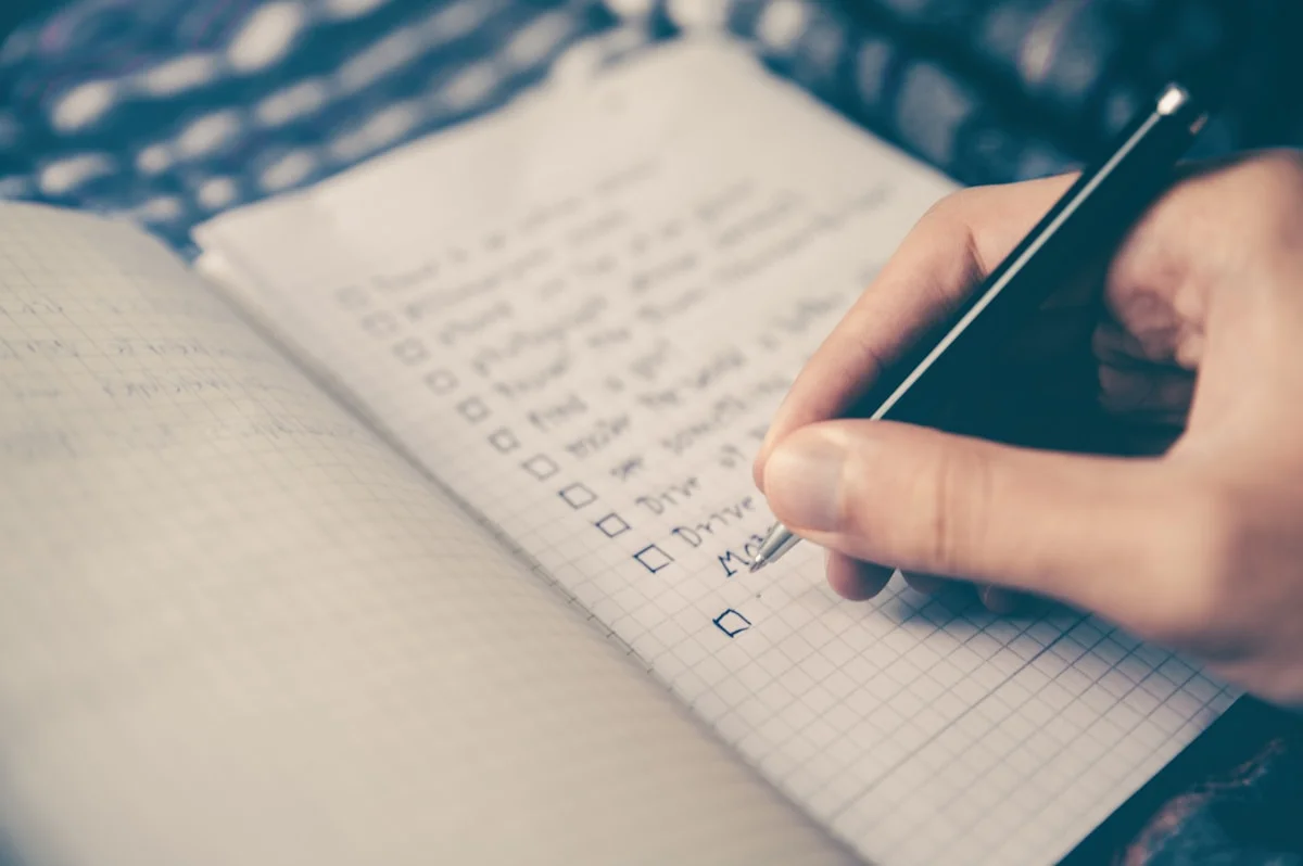A hand writing a numbered list in a notebook.