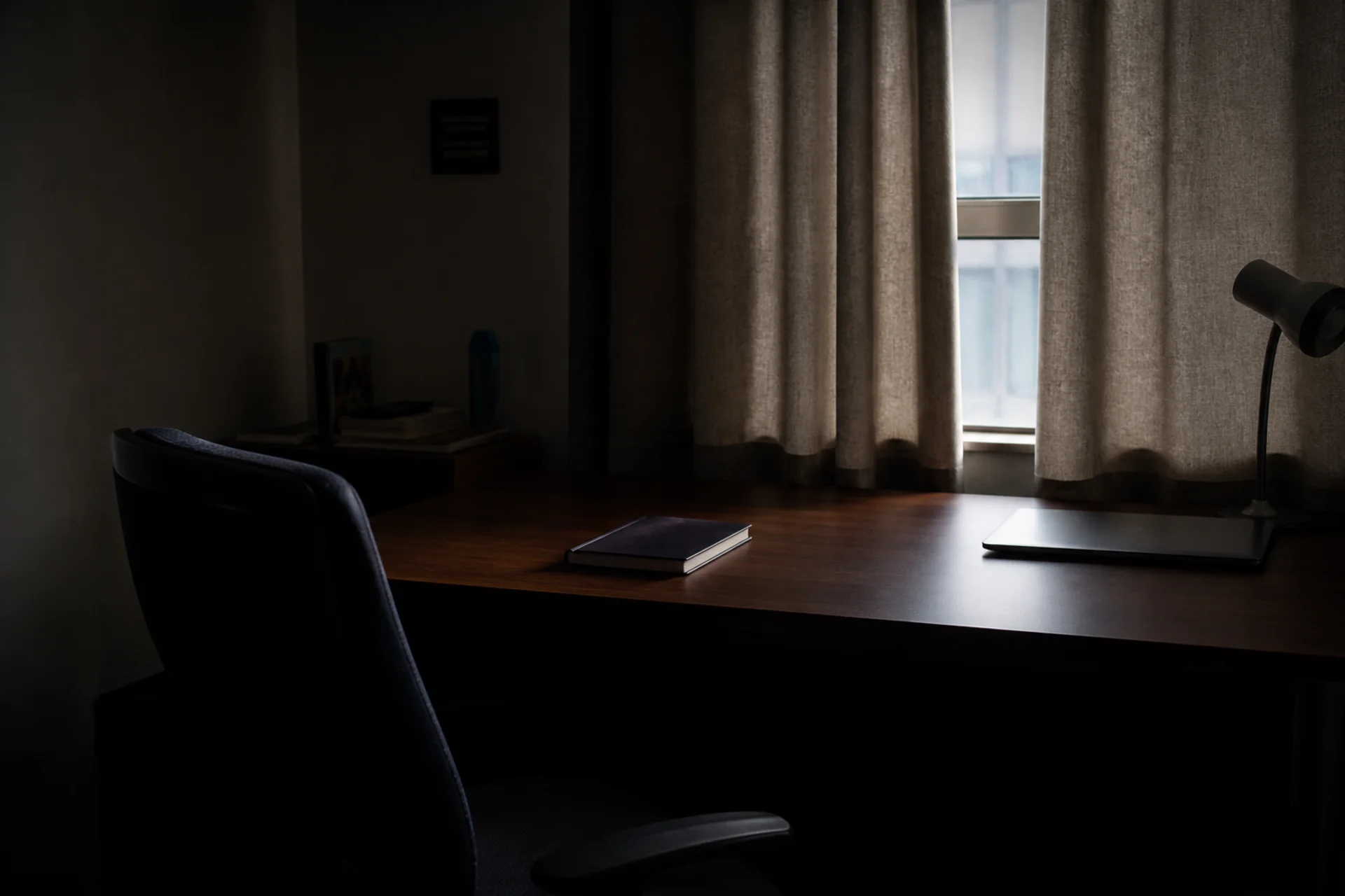 An untouched desk in low light, the chair turned away.