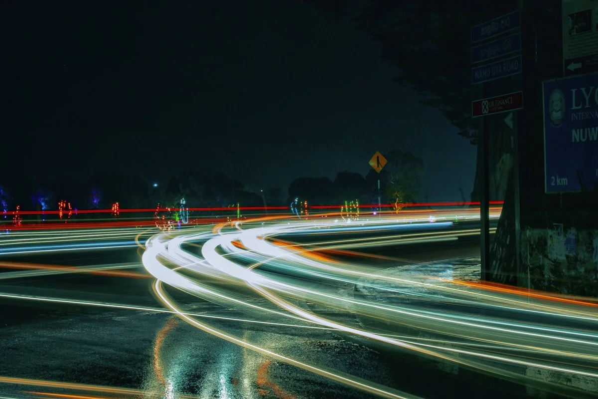 Traffic circling a roundabout in heavy rain, seen from the kerb.