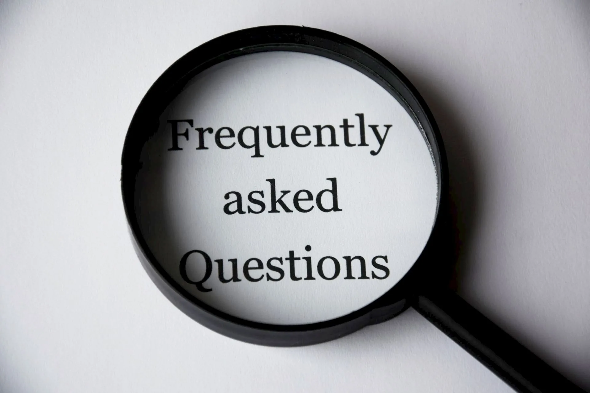 A magnifying glass held over the words frequently asked questions.
