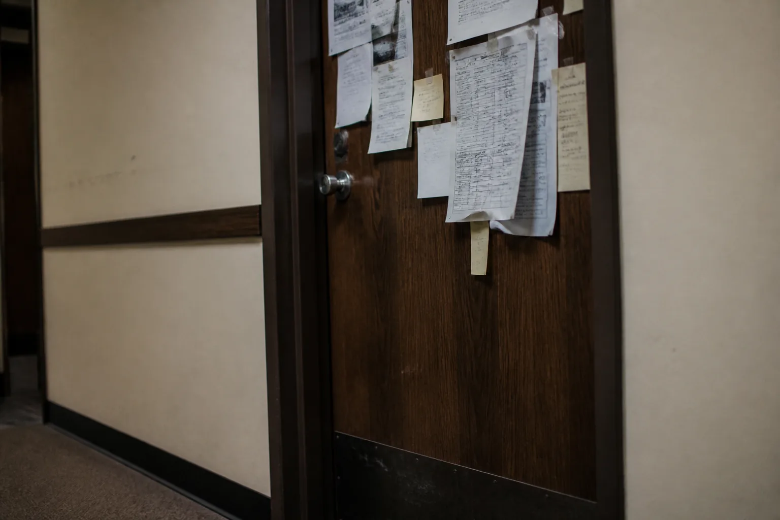 A busy academic office door, layered with schedules and notes.